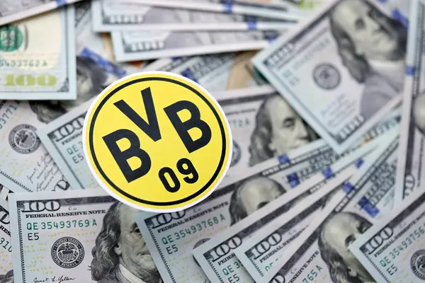 KYIV, UKRAINE - 23 Şubat 2025 Borussia Dortmund futbol kulübü rozeti yüzlük banknotların üzerinde yatıyor