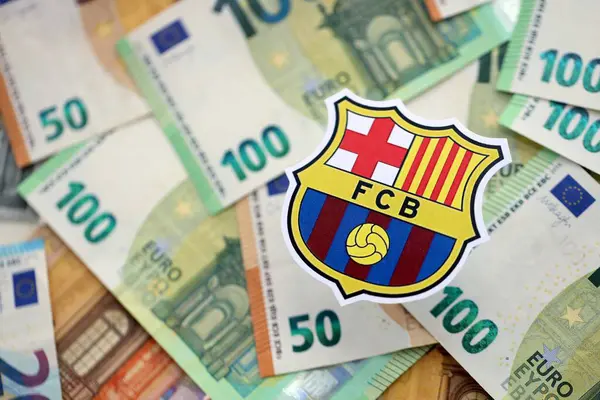KYIV, UKRAINE - 23 Şubat 2025 FC Barcelona futbol kulübü rozeti büyük miktarda EURO para banknotlarının üzerinde yatıyor