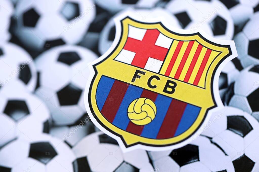 KYIV, UKRAINE - FEBRUARY 23, 2025 FC Barcelona football club badge lies on soccer balls background banner