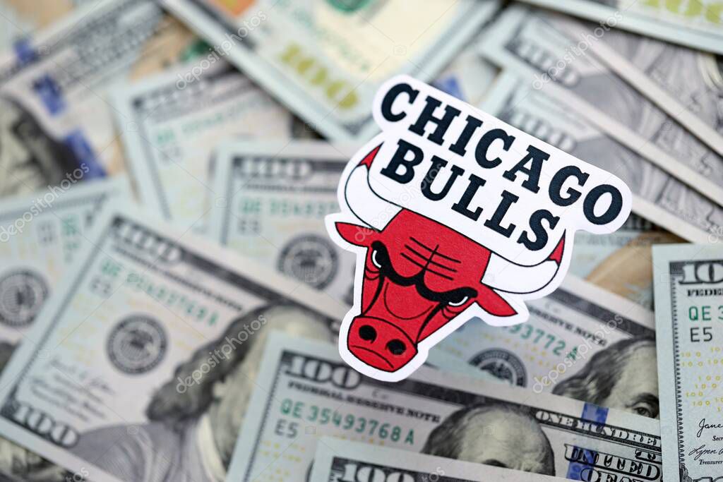 KYIV, UKRAINE - FEBRUARY 23, 2025 Chicago Bulls basketball team badge lies on big amount of hundred US dollar bills close up
