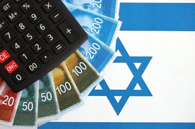 Israel New Shekels banknotları ve hesap makinesi bayrağın üzerinde. İsrail 'in mevcut para faturaları ve kalibreleri büyük oranda bayrakta yatıyor. İsrail 'de vergilendirme ve para kavramı