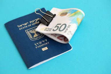 Israel New Shekels banknotları ve mavi arka planda pasaport. İsrail 'in şu anki para banknotları büyük oranda mavi üzerine yatar. İsrail 'de finans ve nakit kavramı