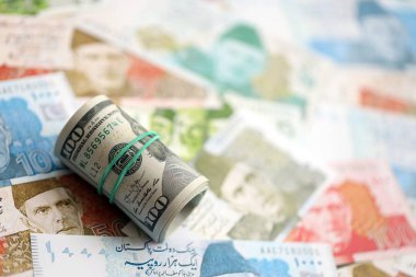 Amerikan dolarlarının rulosu Pakistan 'daki büyük miktardaki banknotların üzerinde yatıyor. Amerikan para demeti Pakistan 'ın para banknotlarında yatıyor. Pakistan 'da ekonomi ve döviz kuru kavramı