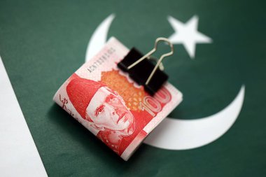 Pakistan bayrağı üzerinde Pakistan banknotları. Pakistan 'ın mevcut para faturaları büyük miktarlarda pankartta yatıyor. Pakistan 'da ekonomi ve ticaret kavramı