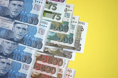 Pakistan banknotları sarı arka planda. Pakistan 'ın mevcut para faturaları büyük miktarda masada yatıyor. Pakistan 'da iş ve yatırım kavramı
