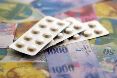 İsviçre frangı ve ilaç hapları. Mevcut para ve uyuşturucu banknotları büyük miktarda masada yatıyor. İsviçre 'de ilaç ve eczane kavramı