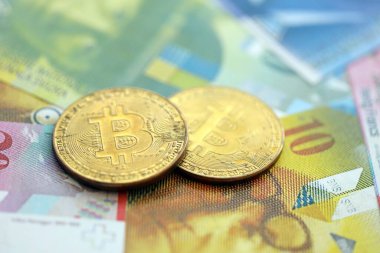 İsviçre frangı banknotları ve bitcoin. Mevcut frank para ve bit para büyük miktarda masada yatıyor. İsviçre 'de vergilendirme ve iş kavramı