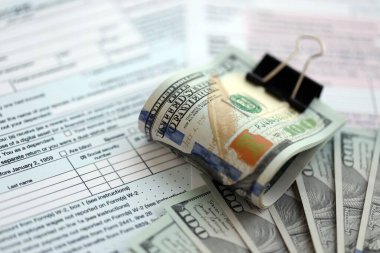 Birleşik Devletler 'in 100 dolarlık banknotları bireysel gelir vergisi iadesi formlarıyla dolu. ABD 'de vergilendirme ve muhasebe kavramı