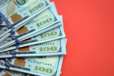 Kırmızı arka planda büyük miktarda yüz dolarlık banknot var. ABD 'de vergilendirme ve para yapma kavramı