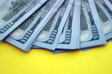 Sarı arka planda büyük miktarda Birleşik Devletler 100 dolarlık banknotları. ABD 'de vergilendirme ve para yapma kavramı