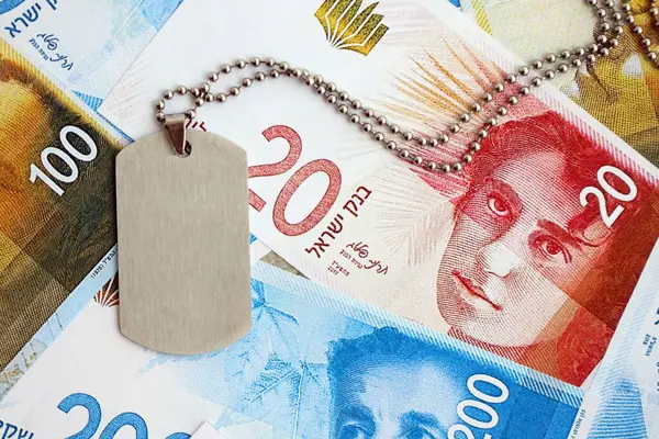 İsrail Yeni Şekelleri 'nin banknotları ve askeri simgesi. İsrail 'in mevcut para faturaları ve künyeleri büyük miktarda masada yatıyor. İsrail 'de askerlik kavramı