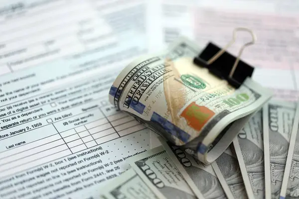 Birleşik Devletler 'in 100 dolarlık banknotları bireysel gelir vergisi iadesi formlarıyla dolu. ABD 'de vergilendirme ve muhasebe kavramı