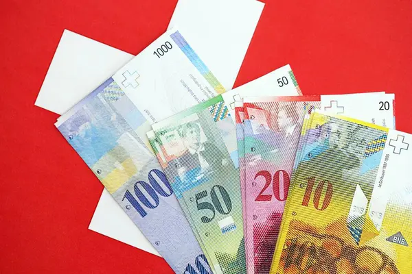 İsviçre frangı banknotları ve bayrağı. Mevcut para banknotları büyük miktarda bayrağın üzerinde yatıyor. İsviçre 'de iş ve yatırım kavramı