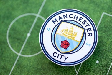 KYIV, UKRAINE - 23 Şubat 2025 Manchester FC futbol kulübü rozeti futbol sahasının arka planında yer almaktadır