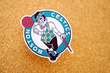 KYIV, UKRAINE - 23 Şubat 2025 Boston Celtics basketbol takımı rozeti altın sarısı parıltılı arka plan afişinde yatıyor