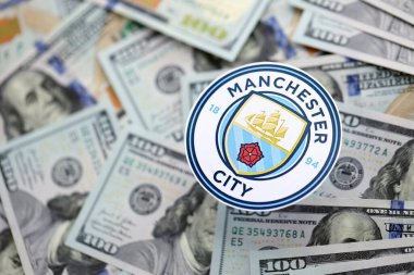 KYIV, UKRAINE - 23 Şubat 2025 Manchester FC futbol kulübü rozeti büyük miktarlarda Amerikan doları üzerinde yer almaktadır.