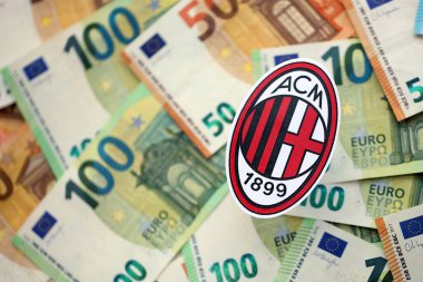 KYIV, UKRAINE - 23 Şubat 2025 AC Milan futbol kulübü rozeti büyük miktarda EURO para banknotları üzerinde yatıyor