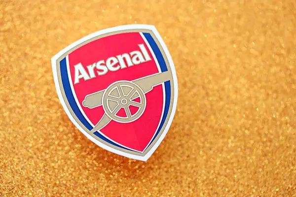 KYIV, UKRAINE - 23 Şubat 2025 Arsenal FC futbol kulübü rozeti altın sarısı parıltılı arka plan pankartıyla uzanır