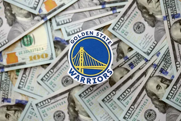 KYIV, UKRAINE - 23 Şubat 2025 Golden State Warriors basketbol takımı rozeti yüzlük banknotların üzerinde.