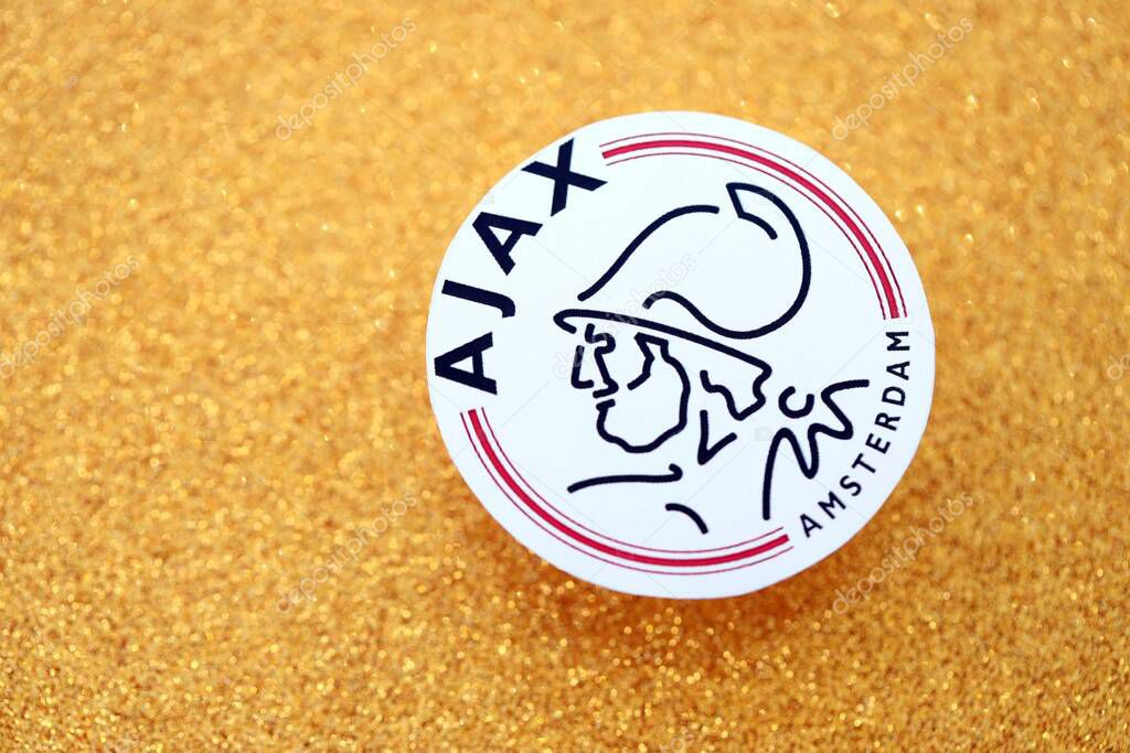 KYIV, UKRAINE - FEBRUARY 23, 2025 AFC Ajax football club badge lies on golden yellow glitter background banner