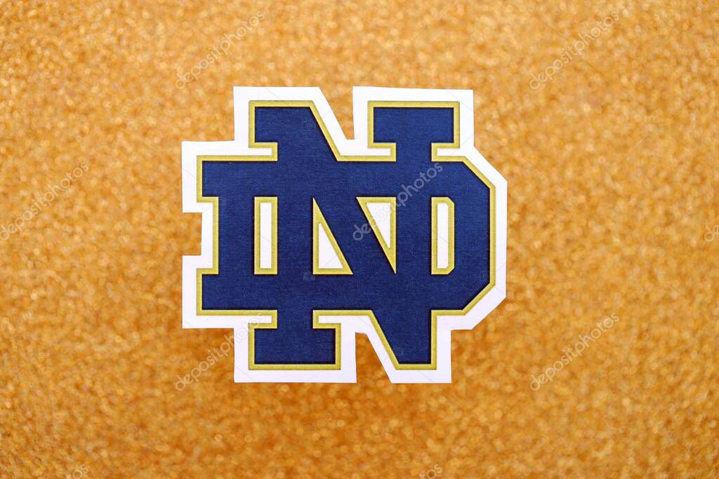 KYIV, UKRAINE - FEBRUARY 23, 2025 Notre Dame Fighting Irish basketball team badge lies on golden yellow glitter background banner