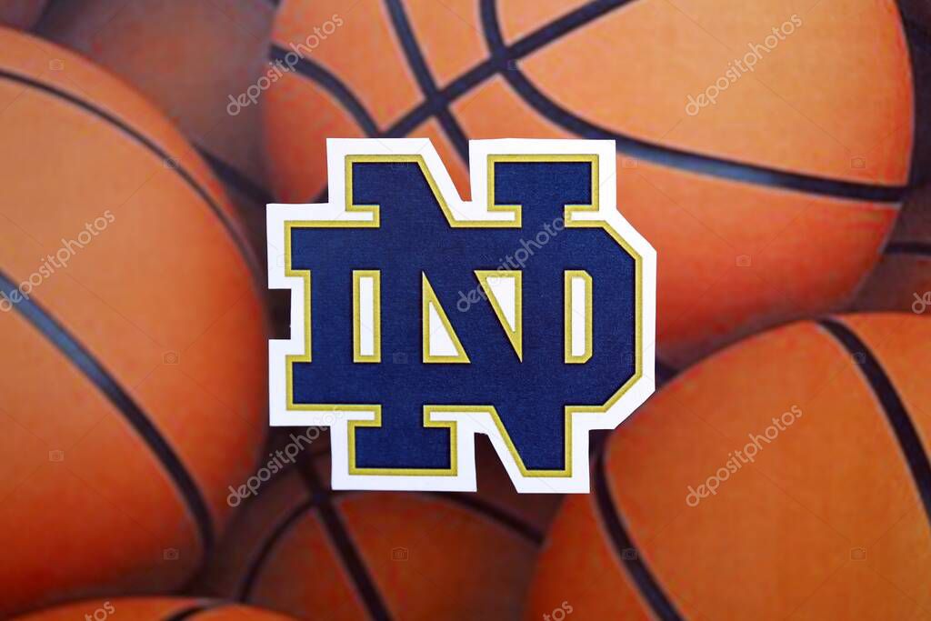 KYIV, UKRAINE - FEBRUARY 23, 2025 Notre Dame Fighting Irish basketball team badge lies on basketball balls background banner