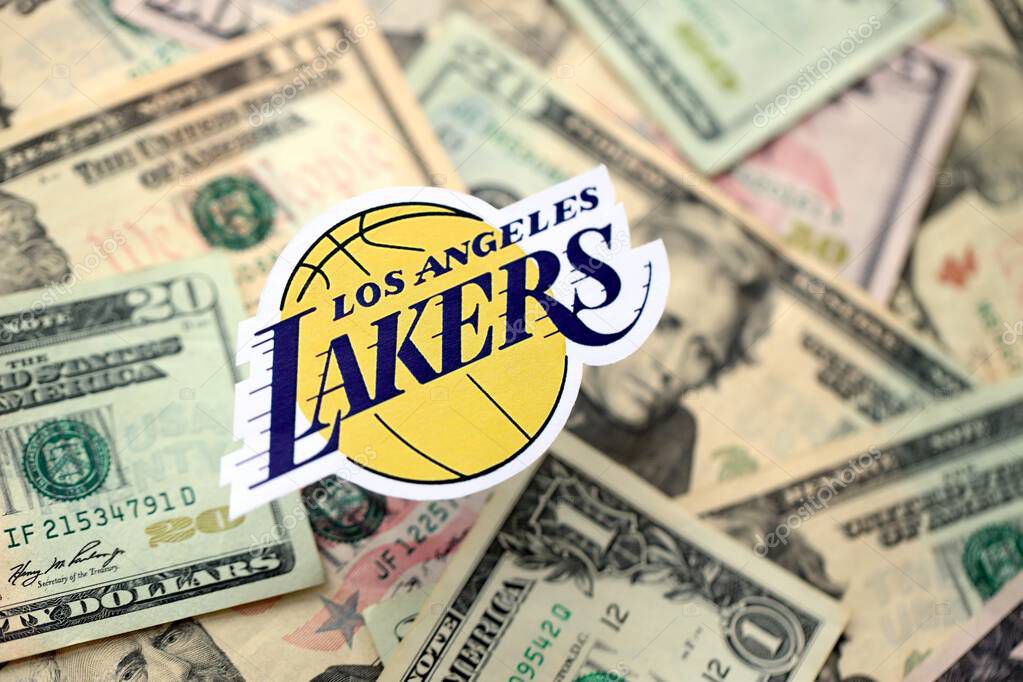KYIV, UKRAINE - FEBRUARY 23, 2025 Los Angeles Lakers basketball team badge lies on big amount of US dollar bills close up
