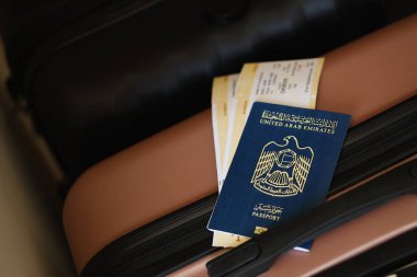 Biletli Birleşik Arap Emirlikleri pasaportu havaalanındaki bekleme salonunun yakınındaki turistik bavulda yatıyor. Dünya çapında seyahat ve uluslararası turizm kavramı