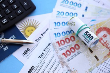 Arjantin Pezosu 'nun para faturaları kalem, hesap makinesi, pasaport ve vergi formlarıyla dolu. Finans ve bankacılık kavramı