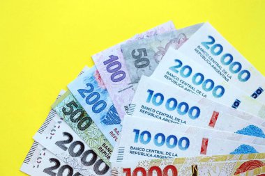 Arjantin pezosu büyük miktarlarda banknotlar sarı renkli masaya yakın duruyor. Finans ve bankacılık kavramı