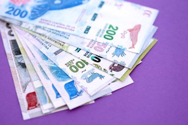 Arjantin pezosu büyük miktarda para mor renkli masaya yakın duruyor. Finans ve bankacılık kavramı