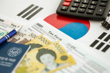 Güney Kore büyük miktarda para kazandı. Masada kalem, hesap makinesi, pasaport ve vergi formları var. Vergi ödeme ve muhasebe kavramı