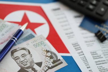 Kuzey Kore büyük miktarlarda para kazandı. Masada kalem, hesap makinesi, pasaport ve vergi formları var. Vergi ödeme ve muhasebe kavramı