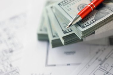 Kalemle birlikte yüklü miktarda Amerikan doları banknotları ve konut projesinin planları yakın plan. Yatırım ve inşaat projesi kavramı