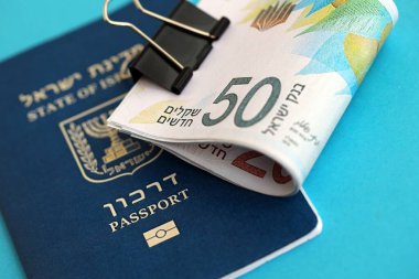 Israel New Shekels banknotları ve mavi arka planda pasaport. İsrail 'in şu anki para banknotları büyük oranda mavi üzerine yatar. İsrail 'de finans ve nakit kavramı