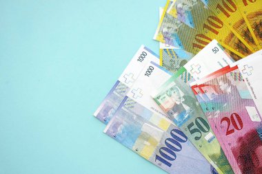 Mavi arka planda İsviçre frangı banknotları. Mevcut frank para faturaları büyük miktarda masada yatıyor. İsviçre 'de iş ve yatırım kavramı