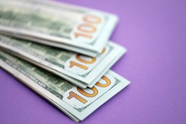 Mor arka planda büyük miktarda yüz dolarlık banknotlar. ABD 'de vergilendirme ve para yapma kavramı