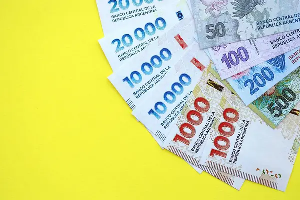 Arjantin pezosu büyük miktarlarda banknotlar sarı renkli masaya yakın duruyor. Finans ve bankacılık kavramı