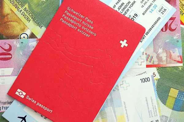 İsviçre frangı banknotları ve biletli pasaport. Mevcut banknotlar ve biyometrik geçiş kartları büyük miktarda masada yatıyor. İsviçre 'de seyahat ve tatil kavramı