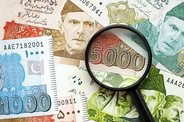 Pakistan banknotları ve büyüteç. Pakistan 'ın mevcut para ve büyüteç faturaları büyük miktarda masanın üzerinde duruyor. Pakistan 'da mali izleme ve vergilendirme kavramı