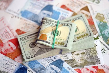 Amerikan dolarları yığını Pakistan Rupi banknotlarının büyük bir miktarına yakın duruyor. Amerikan para demeti Pakistan 'ın para banknotlarında yatıyor. Pakistan 'da ekonomi ve döviz kuru kavramı
