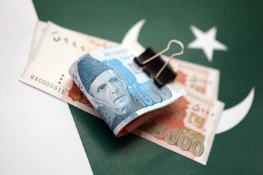 Pakistan bayrağı üzerinde Pakistan banknotları. Pakistan 'ın mevcut para faturaları büyük miktarlarda pankartta yatıyor. Pakistan 'da ekonomi ve ticaret kavramı