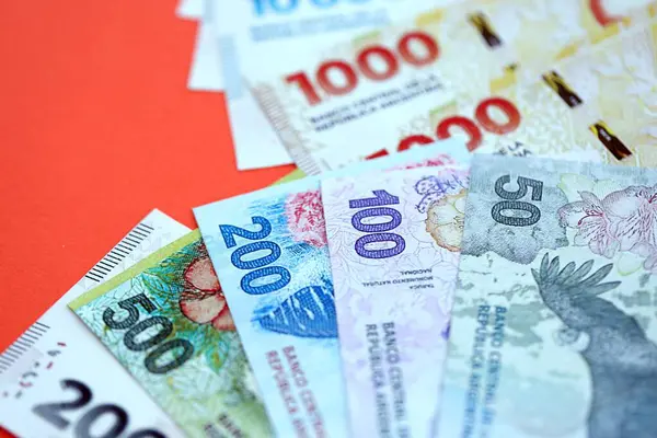 Arjantin pezosu büyük miktarlarda para kırmızı renkli masaya yakın duruyor. Finans ve bankacılık kavramı