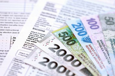 Arjantin pezosu. Büyük miktarda para. Masada, kalem ve vergi formları var.