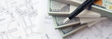 Kalemle birlikte yüklü miktarda Amerikan doları banknotları ve konut projesinin planları yakın plan. Yatırım ve inşaat projesi kavramı