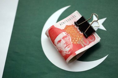 Pakistan bayrağı üzerinde Pakistan banknotları. Pakistan 'ın mevcut para faturaları büyük miktarlarda pankartta yatıyor. Pakistan 'da ekonomi ve ticaret kavramı