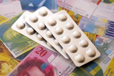 İsviçre frangı ve ilaç hapları. Mevcut para ve uyuşturucu banknotları büyük miktarda masada yatıyor. İsviçre 'de ilaç ve eczane kavramı