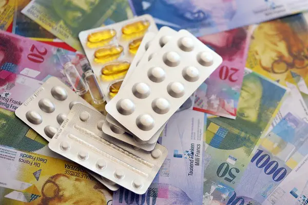 İsviçre frangı ve ilaç hapları. Mevcut para ve uyuşturucu banknotları büyük miktarda masada yatıyor. İsviçre 'de ilaç ve eczane kavramı