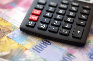 İsviçre frangı banknotları ve hesap makinesi. Mevcut frank para faturaları ve calc büyük miktarda masada yatıyor. İsviçre 'de vergilendirme ve para konsepti