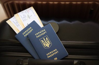 Biletli Ukrayna pasaportu havaalanının bekleme salonunda duran turistik bavulun üzerinde yatıyor. Dünya çapında seyahat ve uluslararası turizm kavramı